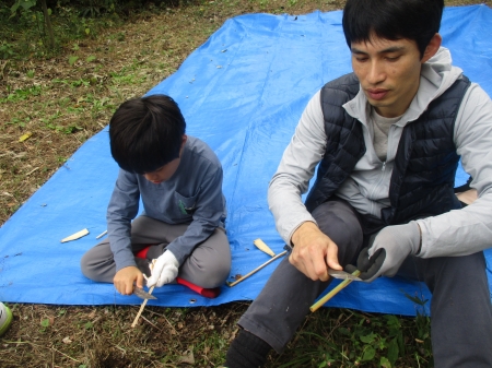 小刀で箸作りをする父子