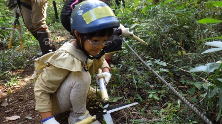 腰を低くして下草刈りをする子ども